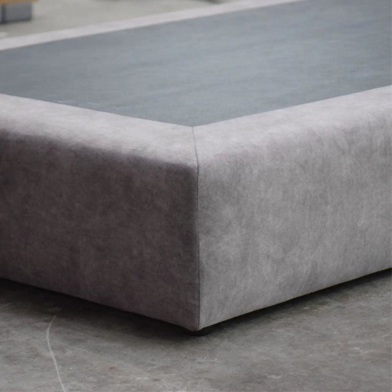 Gray upholstered corner piece on a concrete floor