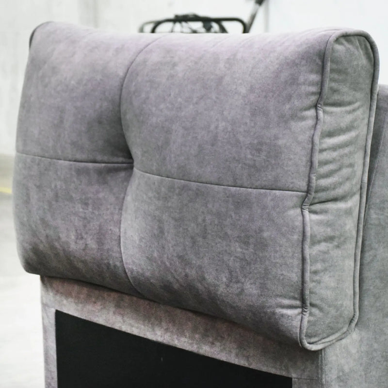 Gray upholstered headboard on a bed with a blurred background