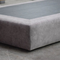 Gray upholstered corner piece on a concrete floor