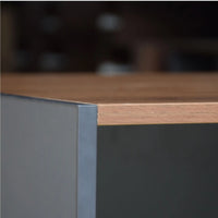 Close-up of a wooden desk with a metallic corner detail, blurred background