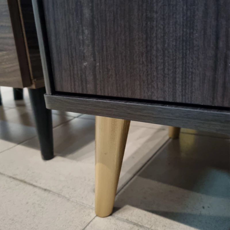 Close-up of a wooden leg of a piece of furniture on a tiled floor.